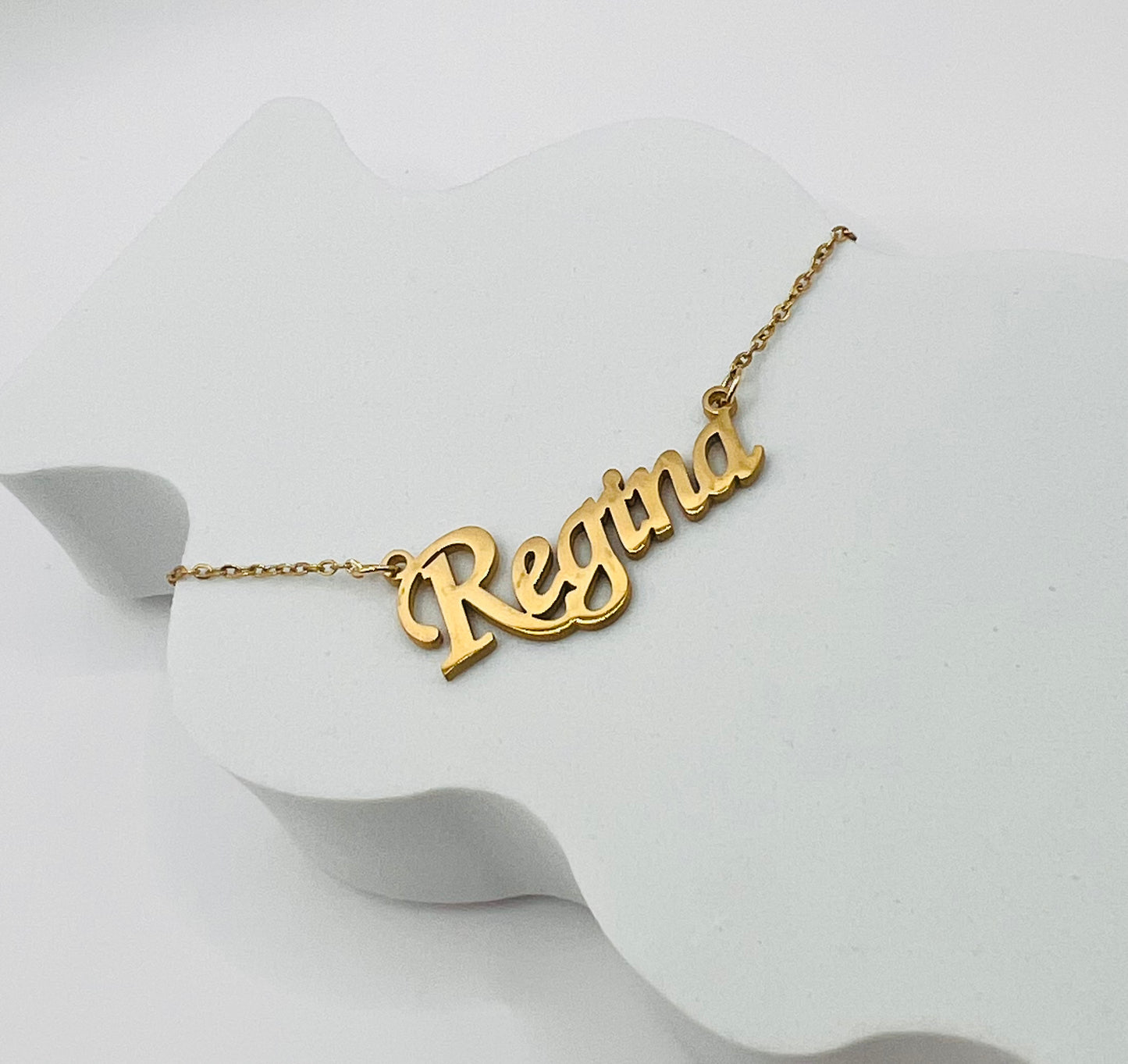 Lleva contigo el dije con tu nombre o el de tu persona amada, reflejando tu identidad con sofisticación y elegancia, un recordatorio constante de quién eres, a quién amas y cómo puedes brillar con tu esencia única - Regina