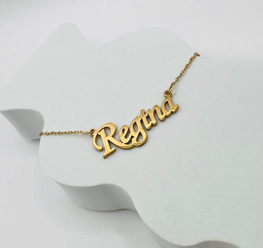 Lleva contigo el dije con tu nombre o el de tu persona amada, reflejando tu identidad con sofisticación y elegancia, un recordatorio constante de quién eres, a quién amas y cómo puedes brillar con tu esencia única - Regina