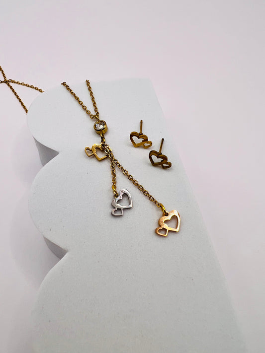 Luce la representación visual del amor que une corazones en un abrazo eterno a través de este hermoso collar con sus aretes, ambos de acero inoxidable.