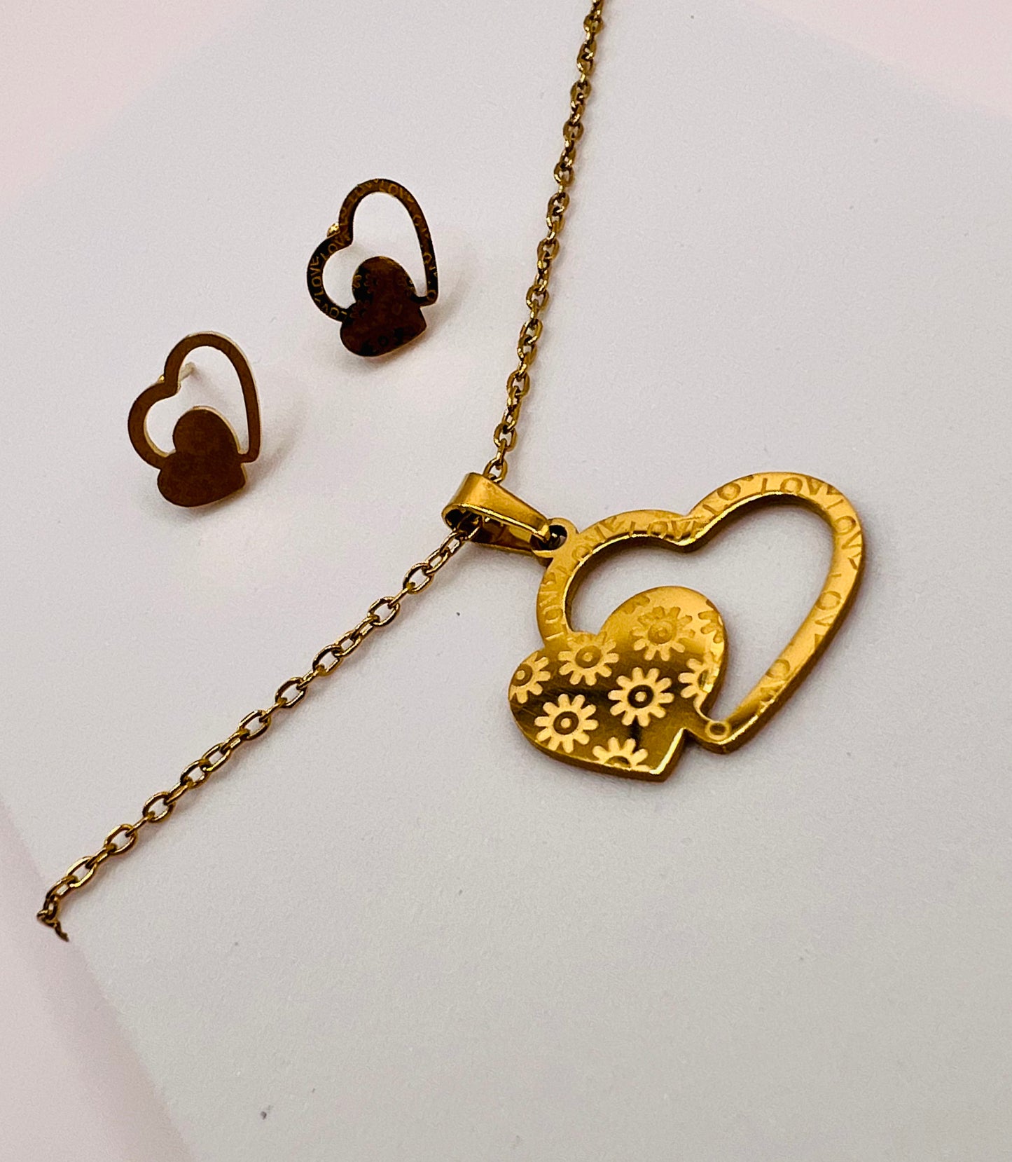 Descubre la elegancia del amor en nuestro conjunto de collar y aretes de acero inoxidable, luciendo un recordatorio constante del amor que abarca tanto el exterior como el interior de tu ser.